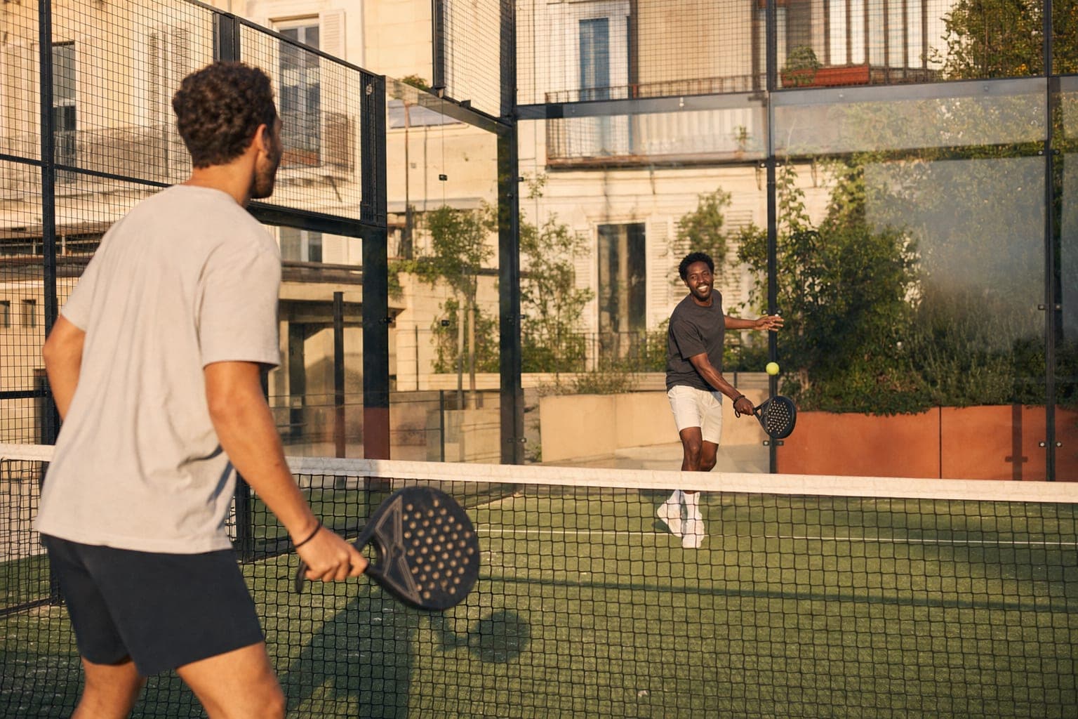 Des joueurs disputent une partie de padel sur un terrain extérieur.